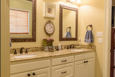 ニューオリンズにある中くらいなコンテンポラリースタイルのおしゃれな浴室 (レイズドパネル扉のキャビネット、白いキャビネット、ベージュの壁、アンダーカウンター洗面器、御影石の洗面台、ベージュの床) の写真