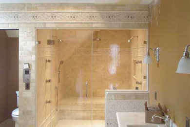 ニューヨークにあるおしゃれなマスターバスルーム (アンダーカウンター洗面器、ライムストーンの洗面台、バリアフリー、分離型トイレ、ベージュのタイル、石タイル、黄色い壁) の写真