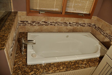 Large elegant master multicolored tile and mosaic tile drop-in bathtub photo in Milwaukee with brown walls, beaded inset cabinets, white cabinets and granite countertops