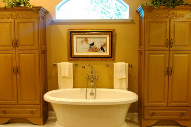 Foto de cuarto de baño tradicional de tamaño medio con armarios con paneles con relieve, puertas de armario de madera oscura, bañera exenta, paredes beige y suelo beige