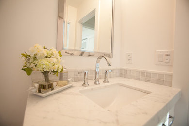 Diseño de cuarto de baño clásico con armarios con rebordes decorativos, puertas de armario blancas, paredes blancas y lavabo encastrado