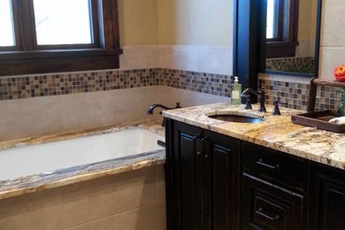 Bathroom - beige tile and stone tile ceramic tile bathroom idea in Kansas City with recessed-panel cabinets, dark wood cabinets and granite countertops