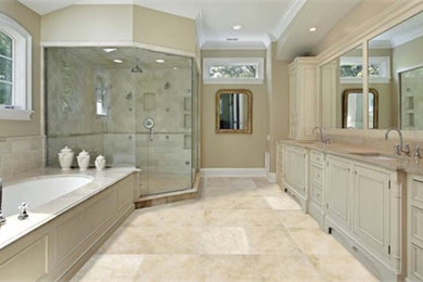Inspiration for a large traditional ensuite bathroom in Sacramento with recessed-panel cabinets, beige cabinets, a submerged bath, a corner shower, grey tiles, stone tiles, beige walls, travertine flooring, a submerged sink, granite worktops, beige floors and a hinged door.