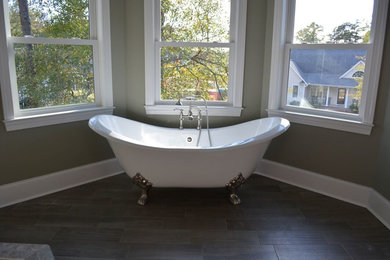 Cette photo montre une grande salle de bain principale victorienne avec une baignoire sur pieds, un mur gris, parquet foncé et un sol marron.