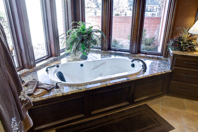 Mid-sized elegant master ceramic tile and beige floor drop-in bathtub photo in Oklahoma City with flat-panel cabinets, dark wood cabinets, brown walls and granite countertops
