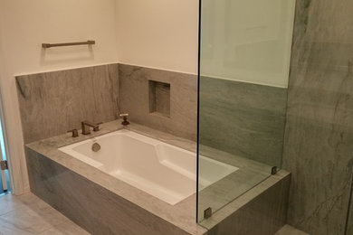 Example of a mid-sized minimalist porcelain tile corner bathtub design in Los Angeles with white walls and marble countertops