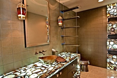 Example of a large trendy master brown tile and ceramic tile ceramic tile and beige floor bathroom design in Phoenix with flat-panel cabinets, dark wood cabinets, a one-piece toilet, brown walls, a vessel sink and onyx countertops