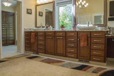 Foto de cuarto de baño principal tradicional de tamaño medio con armarios con paneles con relieve, puertas de armario de madera oscura, paredes beige, lavabo sobreencimera, encimera de granito y suelo beige