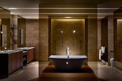 Пример оригинального дизайна: большая главная ванная комната в современном стиле с фасадами с утопленной филенкой, темными деревянными фасадами, отдельно стоящей ванной, коричневой плиткой, каменной плиткой, коричневыми стенами, полом из травертина, накладной раковиной и коричневым полом