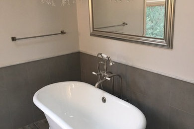 Modelo de cuarto de baño contemporáneo con bañera exenta, baldosas y/o azulejos grises, baldosas y/o azulejos de cerámica, paredes blancas, suelo laminado y suelo gris