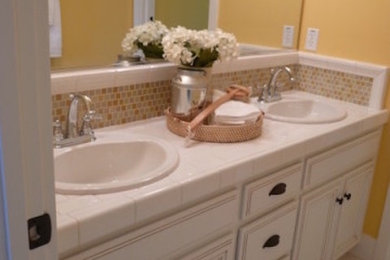 サンフランシスコにある中くらいなトラディショナルスタイルのおしゃれなバスルーム (浴槽なし) (落し込みパネル扉のキャビネット、白いキャビネット、ベージュのタイル、モザイクタイル、黄色い壁、セラミックタイルの床、オーバーカウンターシンク、タイルの洗面台、白い床、白い洗面カウンター) の写真
