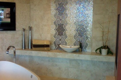 Modelo de cuarto de baño principal mediterráneo de tamaño medio con bañera exenta, encimera de azulejos, baldosas y/o azulejos negros, baldosas y/o azulejos de piedra, paredes beige y suelo de baldosas de terracota