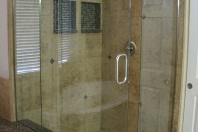 Example of a mid-sized master beige tile bathroom design in Phoenix with glass-front cabinets