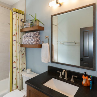 Small kids bathroom in Phoenix with recessed-panel cabinets, medium wood cabinets, an undermount tub, a shower/bathtub combo, a two-piece toilet, black and white tile, porcelain tile, blue walls, brick floors, an undermount sink, engineered quartz benchtops, red floor, a shower curtain and black benchtops.