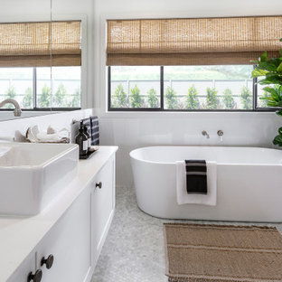 Modern inredning av ett stort vit vitt en-suite badrum, med skåp i shakerstil, vita skåp, ett fristående badkar, en hörndusch, vit kakel, glasskiva, vita väggar, ett fristående handfat och grått golv