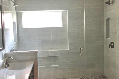 Mid-sized transitional master gray tile and ceramic tile vinyl floor, brown floor and double-sink double shower photo in Austin with shaker cabinets, brown cabinets, a one-piece toilet, an undermount sink, quartz countertops, a hinged shower door, white countertops and a built-in vanity