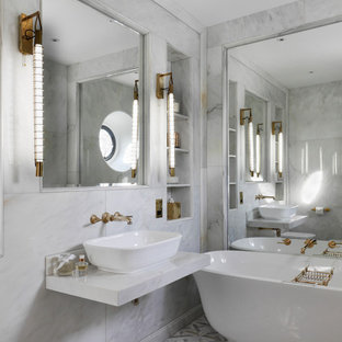 Photo of a large contemporary ensuite bathroom in Oxfordshire with white cabinets, a freestanding bath, marble tiles, marble flooring, multi-coloured floors, white worktops, open cabinets, a wall mounted toilet, grey tiles and a vessel sink.