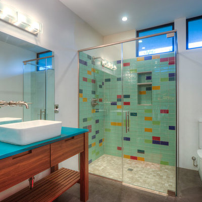 Inspiration for a mid-sized contemporary master glass tile and multicolored tile concrete floor corner shower remodel in Phoenix with a vessel sink, furniture-like cabinets, medium tone wood cabinets, a two-piece toilet, white walls and blue countertops