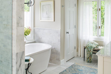 Exemple d'une grande douche en alcôve principale chic avec un lavabo encastré, un placard à porte shaker, des portes de placard blanches, un plan de toilette en marbre, une baignoire indépendante, WC à poser, un carrelage gris, un carrelage de pierre et un mur beige.