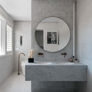 Design ideas for a large contemporary master bathroom in Sydney with a freestanding tub, white tile, stone tile, white walls, ceramic floors, an undermount sink, granite benchtops, white floor and white benchtops.