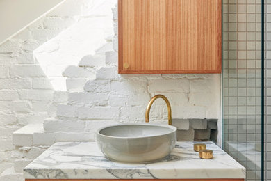 Cette image montre une salle de bain design en bois brun avec un placard à porte shaker, un carrelage blanc, mosaïque, un mur blanc, un sol en carrelage de terre cuite, une vasque et un plan de toilette blanc.