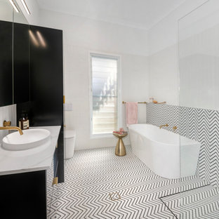 Design ideas for a large contemporary kids bathroom in Brisbane with furniture-like cabinets, black cabinets, a freestanding tub, an open shower, a wall-mount toilet, black and white tile, ceramic tile, white walls, ceramic floors, a vessel sink, marble benchtops, black floor, an open shower, white benchtops, a single vanity and a floating vanity.
