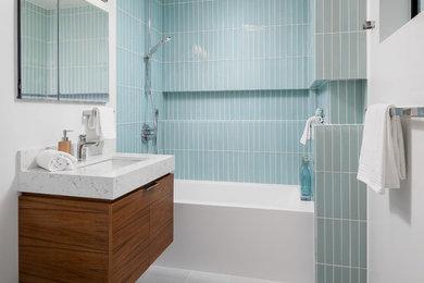 ロサンゼルスにあるコンテンポラリースタイルのおしゃれな浴室 (フラットパネル扉のキャビネット、中間色木目調キャビネット、壁掛け式トイレ、青いタイル、白い壁、スレートの床、壁付け型シンク、大理石の洗面台、グレーの床、シャワーカーテン、白い洗面カウンター) の写真