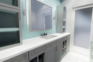 Mid-sized transitional 3/4 white tile and glass tile porcelain tile corner shower photo in Miami with flat-panel cabinets, gray cabinets, a one-piece toilet, gray walls, an undermount sink and solid surface countertops