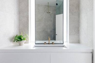Foto på ett funkis badrum med dusch, med släta luckor, vita skåp, beige kakel, marmorkakel, marmorgolv, ett undermonterad handfat och grått golv