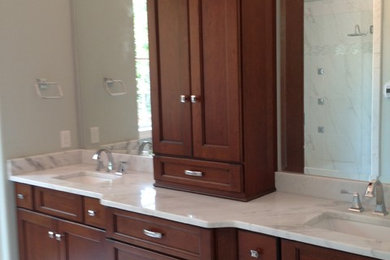 Imagen de cuarto de baño principal tradicional de tamaño medio con armarios con paneles empotrados, puertas de armario de madera en tonos medios y encimera de mármol