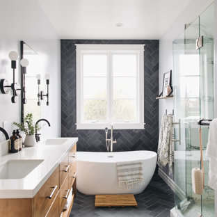 Photo of a mid-sized transitional master bathroom in San Francisco with flat-panel cabinets, medium wood cabinets, a freestanding tub, an alcove shower, a two-piece toilet, black tile, slate, grey walls, slate floors, an undermount sink, engineered quartz benchtops, black floor, a hinged shower door, white benchtops, an enclosed toilet, a double vanity and a floating vanity.