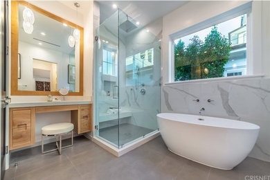 Large trendy master gray tile and porcelain tile mosaic tile floor and gray floor bathroom photo in Los Angeles with flat-panel cabinets, medium tone wood cabinets, a one-piece toilet, white walls, an undermount sink, quartz countertops and a hinged shower door
