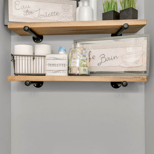 Foto de cuarto de baño con ducha, rústico, pequeño, con armarios estilo shaker, puertas de armario marrones, sanitario de dos piezas, baldosas y/o azulejos grises, paredes grises, suelo laminado, lavabo integrado, encimera de cuarcita, suelo marrón y encimeras blancas