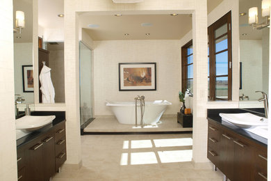 Large contemporary ensuite bathroom in Denver with flat-panel cabinets, dark wood cabinets, a freestanding bath, beige walls, porcelain flooring, a vessel sink, engineered stone worktops and beige floors.