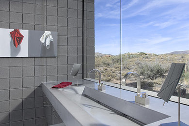 Example of a large trendy master ceramic tile marble floor and white floor bathroom design in Phoenix with flat-panel cabinets, gray cabinets, gray walls, concrete countertops and a trough sink