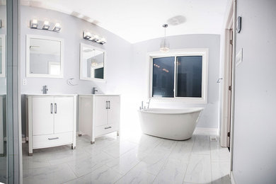 Modelo de cuarto de baño principal contemporáneo grande con armarios con paneles lisos, bañera exenta, sanitario de dos piezas, baldosas y/o azulejos de vidrio, paredes grises y lavabo bajoencimera