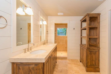 Mid-sized transitional master stone tile travertine floor and beige floor alcove shower photo in Portland with raised-panel cabinets, medium tone wood cabinets, white walls, an undermount sink, quartz countertops and a hinged shower door