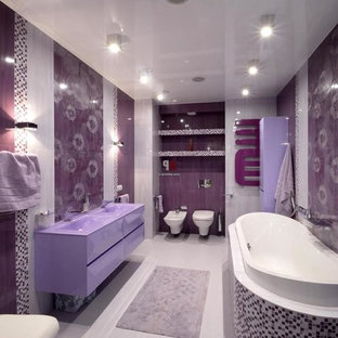 Ispirazione per una grande stanza da bagno padronale design con ante lisce, ante viola, vasca da incasso, WC sospeso, piastrelle di vetro, pareti viola, pavimento in gres porcellanato, lavabo integrato e pavimento grigio