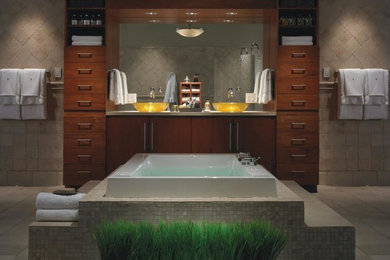 Example of a transitional beige tile beige floor drop-in bathtub design in Las Vegas with flat-panel cabinets, medium tone wood cabinets, beige walls, a vessel sink and quartz countertops
