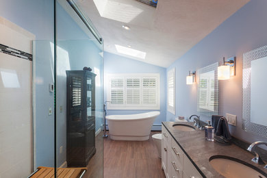 Inredning av ett modernt en-suite badrum, med ett undermonterad handfat, vita skåp, ett fristående badkar, en hörndusch, en toalettstol med separat cisternkåpa, vit kakel, keramikplattor och blå väggar
