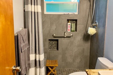 Стильный дизайн: ванная комната среднего размера в стиле модернизм с фасадами с выступающей филенкой, серыми фасадами, открытым душем, унитазом-моноблоком, серой плиткой, керамической плиткой, серыми стенами, полом из керамогранита, душевой кабиной, накладной раковиной, столешницей из гранита, разноцветным полом, шторкой для ванной и бежевой столешницей - последний тренд