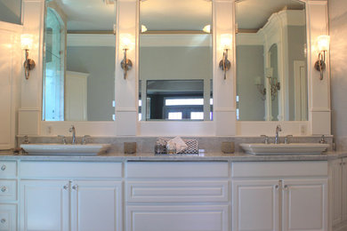 Ejemplo de cuarto de baño principal clásico de tamaño medio con lavabo sobreencimera, puertas de armario blancas, encimera de mármol, baldosas y/o azulejos de piedra, paredes grises y suelo de mármol