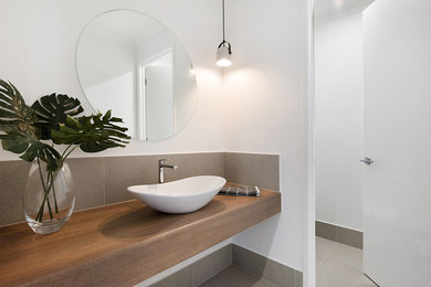 Ejemplo de cuarto de baño moderno con puertas de armario de madera clara, baldosas y/o azulejos grises, lavabo sobreencimera y encimera de madera