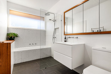 Trendy white tile black floor and single-sink bathroom photo in Melbourne with flat-panel cabinets, white cabinets, white walls, an integrated sink, white countertops, a floating vanity and a niche