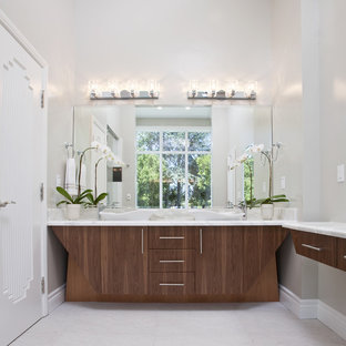 Diseño de cuarto de baño minimalista con encimera de mármol, lavabo sobreencimera, puertas de armario de madera oscura y paredes blancas