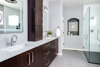 Inspiration for a transitional master white tile walk-in shower remodel in Denver with flat-panel cabinets, dark wood cabinets, quartz countertops, a hinged shower door and white countertops