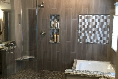 This is an example of a large modern ensuite wet room bathroom in Denver with shaker cabinets, grey cabinets, a two-piece toilet, grey tiles, porcelain tiles, grey walls, porcelain flooring, a submerged sink, granite worktops, grey floors, a hinged door and a submerged bath.