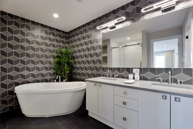 Modern inredning av ett en-suite badrum, med släta luckor, vita skåp, ett fristående badkar, ett undermonterad handfat, svarta väggar och svart golv