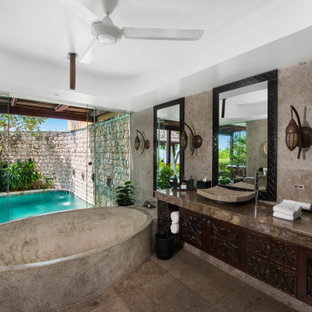 Photo of a tropical bathroom in Gold Coast - Tweed with dark wood cabinets, a freestanding tub, a vessel sink, brown floor, brown benchtops, a double vanity and a built-in vanity.