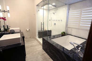 Example of a mid-sized trendy master white tile corner shower design in Salt Lake City with recessed-panel cabinets, black cabinets, an undermount tub, gray walls, a vessel sink, granite countertops and a hinged shower door